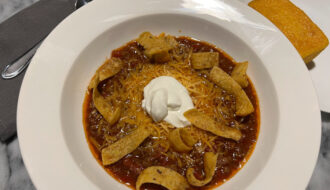 homemade chill topped with cheese, sour cream and fritos with side of cornbread