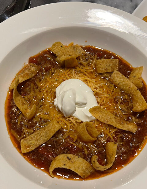 homemade chill topped with cheese, sour cream and fritos with side of cornbread