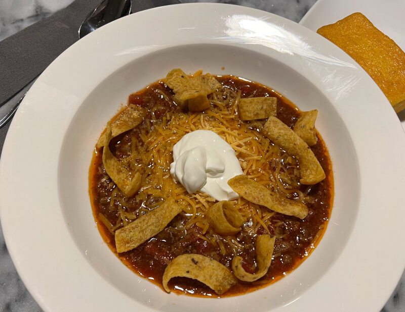 homemade chill topped with cheese, sour cream and fritos with side of cornbread