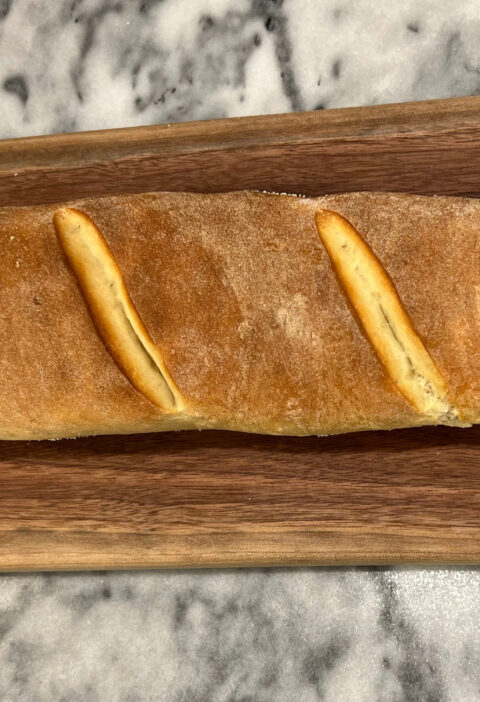 baguette recipe full loaf golden crust on a wooden cutting board