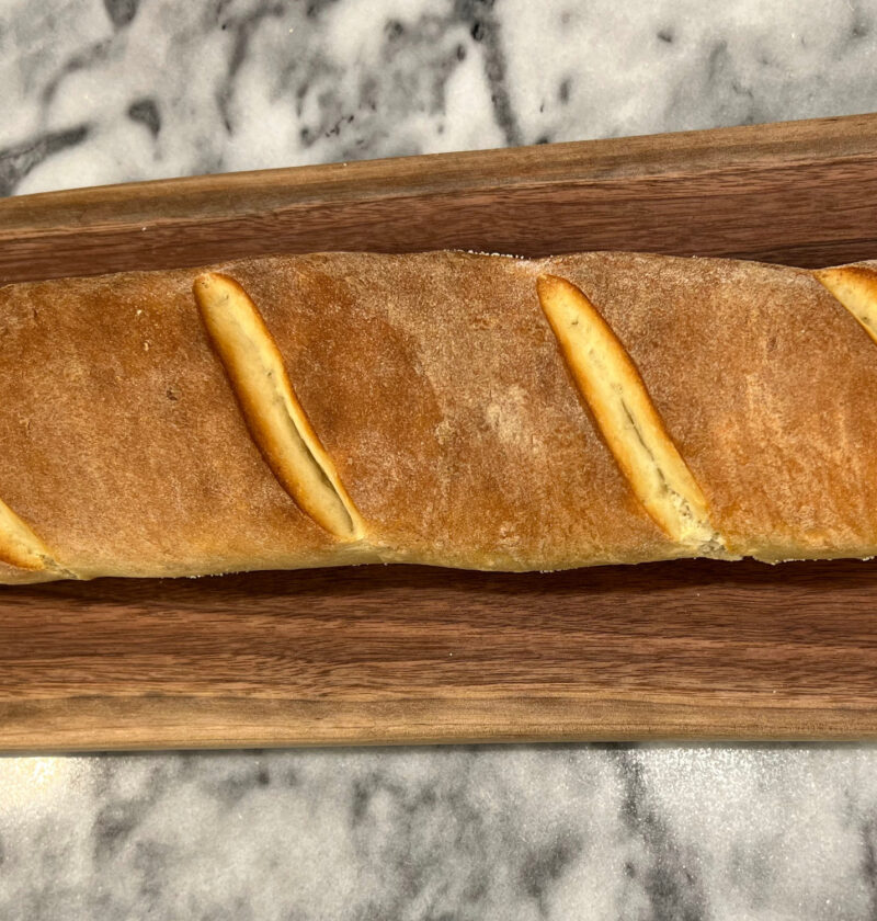 baguette recipe full loaf golden crust on a wooden cutting board